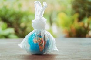 earth day concept globe in plastic zak op tafel foto