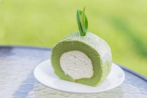 groene theecake en broodje met theeblad op witte schotel. foto