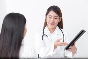een aziatische vrouwelijke arts praat met een vrouwelijke patiënt over zijn pijn en symptomen in het ziekenhuis. foto