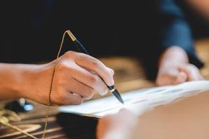 zakenman persoon die een pen gebruikt om een overeenkomst te ondertekenen document papier om goed te keuren door handtekening, hand van zakenman die werkt aan financiën advocaat contract papierwerk in kantoor, concept van deal op business desk foto