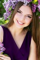 mooi meisje met krans van lila bloemen foto