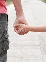 vader houdt de hand van het kind vast om samen te lopen foto