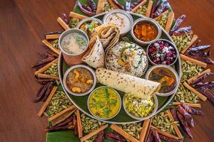 Indiaas eten curry boter kip, palak paneer, chiken tikka, biryani, groentecurry, papad, dal, palak sabji, jira alu, rijst met saffraan op donkere achtergrond foto