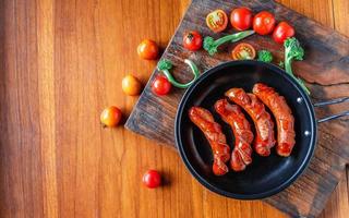 gebakken worstjes in een pan met tomaten en broccoli foto