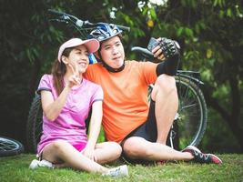 Aziatische man en vrouw nemen een foto met een smartphone na het fietsen in het buitenpark