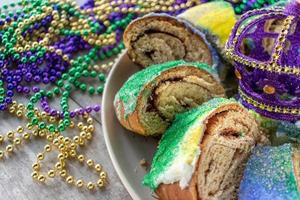 gesneden mardi gras king cake omringd door kleurrijke kralen foto