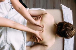 massagetherapeut doet massage op het vrouwelijk lichaam in de spa. het concept van cosmetische procedures. foto