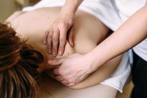 massagetherapeut doet massage op het vrouwelijk lichaam in de spa. het concept van cosmetische procedures. foto