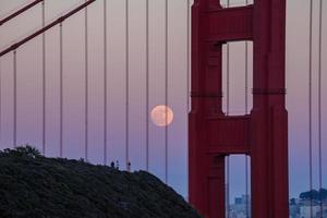 majestueuze san francisco golden gate bridge met juni 2022 volle maan die opkomt en de noordelijke toren gezien vanaf de landtongen van marin in californië foto