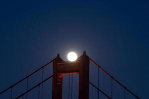 majestueuze san francisco golden gate bridge met juni 2022 volle maan die opkomt en de noordelijke toren gezien vanaf de landtongen van marin in californië foto
