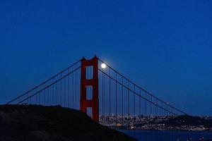 majestueuze San Francisco Bay Bridge met juni 2022 volle maan die naast de noordelijke toren opkomt foto