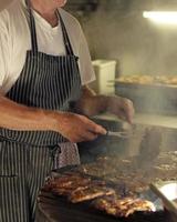 man met een schort aan het werk op de barbecue foto