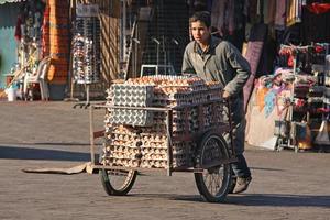 Marrakech, Marokko - 12 september 2021 - een vermoeide jongen duwt een kar vol eierdozen door het oude centrum van Marrakech foto