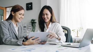 twee gelukkige zakenvrouwen werken samen met een laptop op een desktop op kantoor foto