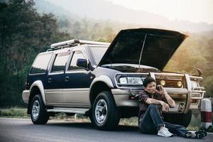 man probeert een automotorprobleem op een lokale weg op te lossen Chiang Mai Thailand - mensen met een autoprobleem transportconcept foto