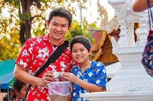 thaise familie neemt deel aan oude traditionele activiteit in een tempel tijdens songkran-festival in chiang mai, noordelijk thailand, zeer beroemde gebeurtenis van thailand foto