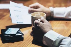 man met koffiekopje en instapkaart wachtend op vliegreizen per vliegtuig voor zakelijk werk foto