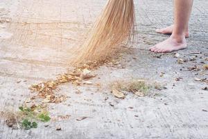 man die de buitenweg schoonmaakt met behulp van bloei gemaakt van droog kokosnootverlofproduct - het levensstijlconcept van de lokale bevolking in thailand foto