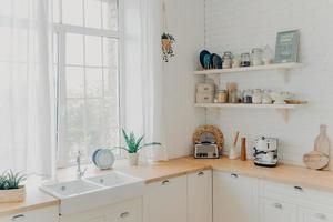 helder verlichte scandinavische keuken met groot raam. concept van hypotheek en modern appartement. foto