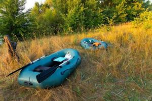 twee rubberboten met visgerei in de vroege ochtend tijdens de mist, geparkeerd aan de oevers van de rivier. foto