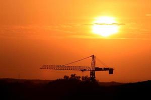industrieel landschap met silhouetten van kranen op de zonsondergang achtergrond foto