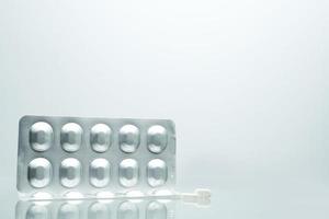 zilveren aluminiumfolie blisterverpakking van pillen met 2 witte tabletpillen op witte achtergrond met schaduwen en kopieer ruimte voor tekst. farmaceutische verpakking en medicijnopslagconcept foto