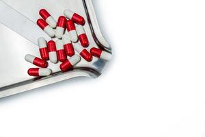 bovenaanzicht van rood-witte antibiotische capsulepillen op roestvrijstalen medicijnbakje. resistentie tegen antibiotica. voorgeschreven medicijnen. farmaceutische industrie. foto