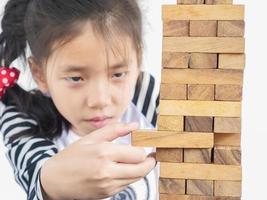 Aziatische jongen speelt jenga, een torenspel met houten blokken om fysieke en mentale vaardigheden te oefenen foto