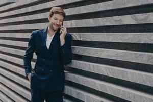 succesvolle zakenman belt via smartphone tijdens werkonderbrekingsgesprekken met zakenpartner foto