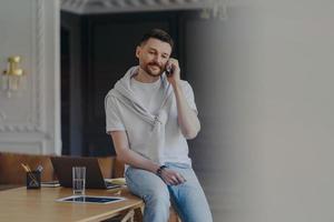 freelancer die aan de telefoon praat terwijl hij op het bureau thuis zit foto