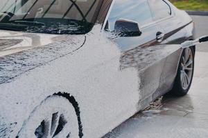 auto reinigen onder hoge druk, speciale waszeep op voertuig spuiten met hogedrukreiniger buitenshuis foto