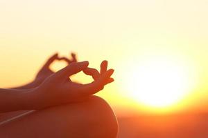 vrouwenhanden die yoga uitoefenen bij zonsondergang