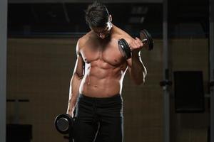 bodybuilder die biceps met domoren uitoefenen foto