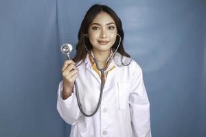 portret van een jonge Aziatische vrouw arts, een medische professional lacht en draagt een stethoscoop geïsoleerd over blauwe achtergrond foto