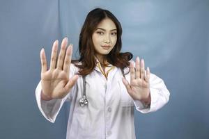 serieuze aziatische vrouwelijke arts met stethoscoop en witte jas, met stopbord. foto