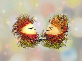 tweeling gedeeltelijk gepelde rambutans met gezicht en hand tekenen voor paar liefde concept over wazig harten bokeh achtergrond foto