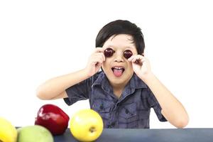 Aziatische gezonde jongen die gelukkige uitdrukking met verscheidenheids kleurrijk fruit en groente toont op witte achtergrond foto