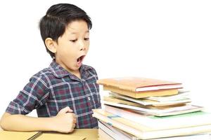 Aziatische jongen schreeuwt terwijl hij naar een stapel boeken kijkt die op een witte achtergrond zijn geïsoleerd foto