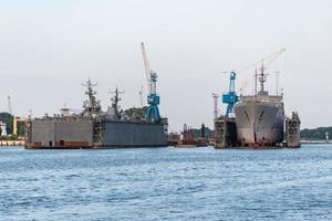 grote ijzeren marineschepen in scheepswerf voor reparatie. grote kraan in de werf. blauwe zee haven foto