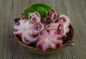 gemarineerde octopus in een kom op houten achtergrond foto