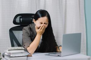 Aziatische vrouw geeuwen tijdens het werken op laptop in haar kantoor. foto