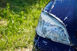 koplamp van auto in schuim. auto wassen in garage voor huis. auto schoonmaken. foto