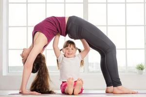 jonge moeder en dochter doen yoga oefening foto