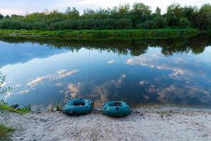 twee rubberboten met visgerei in de vroege ochtend tijdens de mist, geparkeerd aan de oevers van de rivier. foto