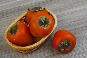 persimmon in een mand op houten achtergrond foto