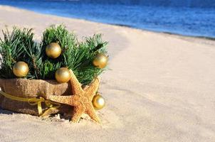 kerstboom met gouden kerstballen, zeester op zand, strand