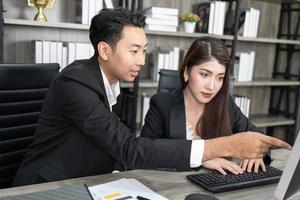 zakenman die iets toont aan collega op desktopcomputer in kantoor. zakenman en vrouw werken samen foto