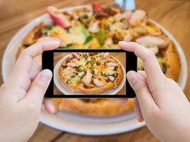 vrouw die foto van pizza neemt met mobiele smartphone