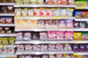 abstracte vervaging supermarkt met verschillende snacks chips voedsel product in de schappen in de winkel foto