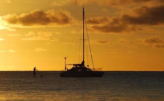 zonsondergang met catamaran en peddelboarder